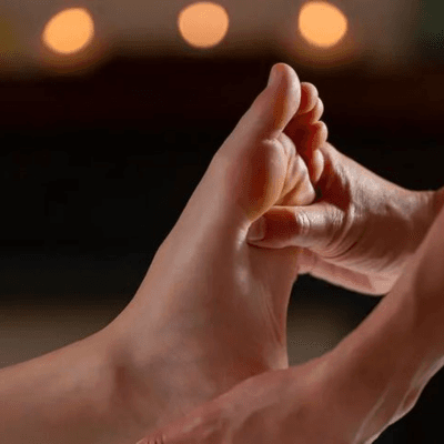 Close-up of a therapist performing foot reflexology by candlelight at Anantara Spa Gachibowli
