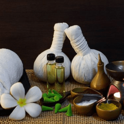Traditional herbal compress balls, essential oils, and frangipani flowers used in Balinese and Thai therapies